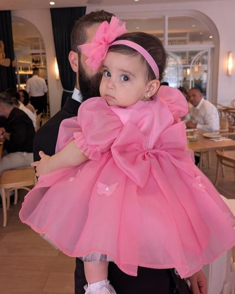 A father holding his daughter in a pink bow Babiesfrock dress and matching hair bow